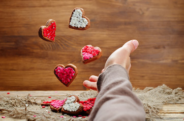 Male hand with flying cookies in the forms of hearts