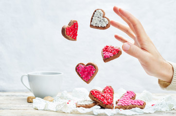 Male hand with flying cookies in the forms of hearts