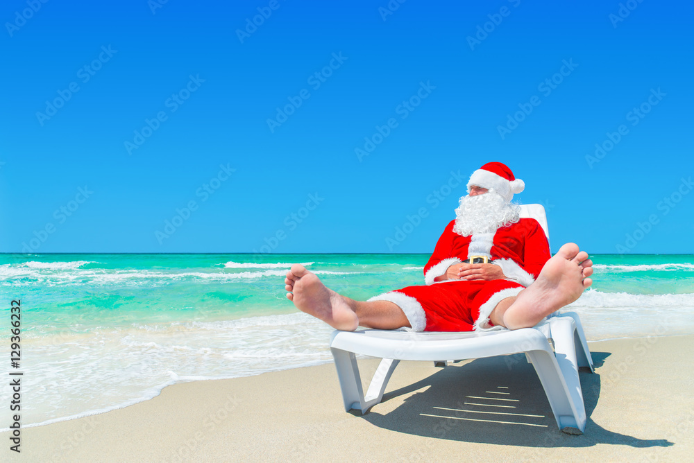 Sticker Christmas Santa Claus relax on sunlounger at ocean tropical beach