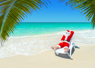 Fototapeta na wymiar Christmas Santa Claus relax in sunlounger at ocean tropical sandy palm beach - Xmas and New Year's travel destinations to hot south countries concept