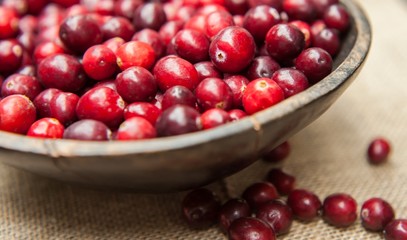 Fresh cranberries  in rustic wooden bowl on burlap Background an