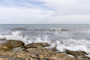 Rocky beach with waves in Santa Pola, Alicante province, Spain.