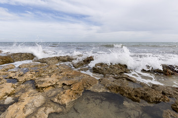 Rocky beach with waves in Santa Pola, Alicante province, Spain.