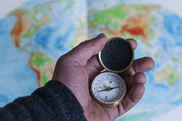 Hand haelt Kompass vor Weltkarte / Hand haelt Kompass vor Weltkarte, geringe Tiefenschaerfe.