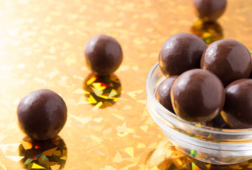Round chocolate candy in small glass cup on colorful background