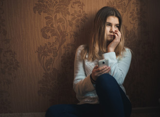 Teen girl excessively sitting at the phone at home. he is a victim of online bullying Stalker...