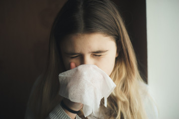 Teen girl wipes her nose on a handkerchief