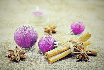 Fototapeta na wymiar Purple christmas balls on white snow. Beautiful christmas close-up decoration postcard. Cinnamon, star anise and candle on sugar snow background.