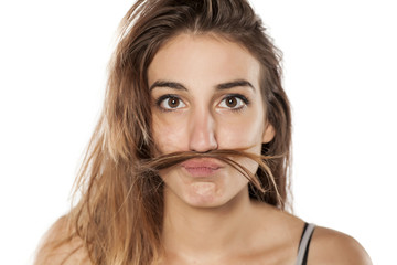 Young funny woman making a mustache with her hair