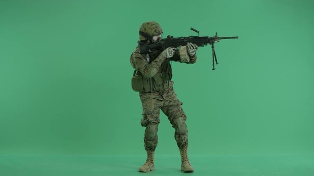 serviceman standing and targeting around at green screen