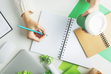 Woman with coffee writing in notepad