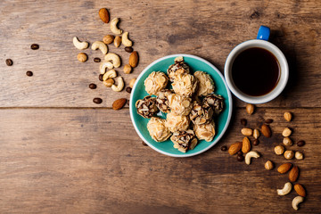 Chocolate candies coffee and nuts over wooden background. Above.