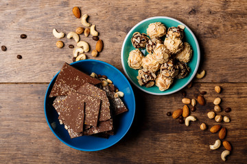 Chocolate candies and nuts over wooden background. Above.