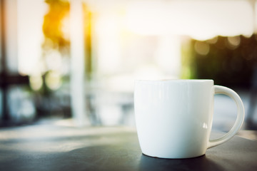 A coffee cup and blur background at outdoor coffee cafe shop with evening morning light.