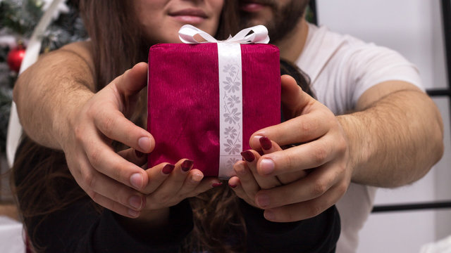 Hands of couple giving a red Christmas gift