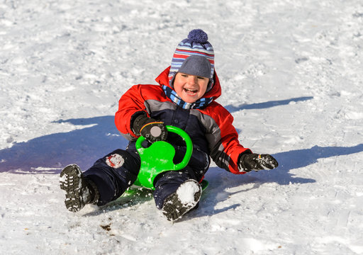Little boy enjoying a sleigh ride. Children play outdoors in sno