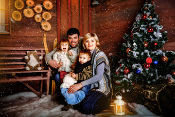 Happy family sitting near a Christmas tree in the evening in anticipation of Christmas