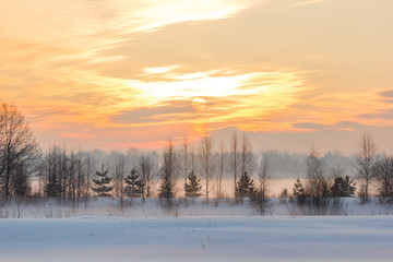 Sunset over the village and the winter fog.