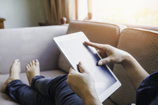 Woman using tablet at home, lying on the sofa