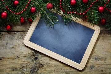 Fir tree branches with red christmas balls and a slate writing board