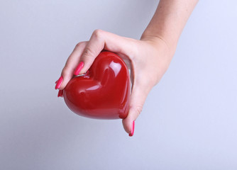 doctor with stethoscope examining red heart, isolated on white