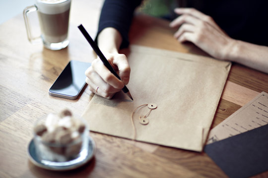 Close-up of hands, working, writing in a restaurant. Envelopes, phone, coffee, Business concept. Stationery blank layouts for design