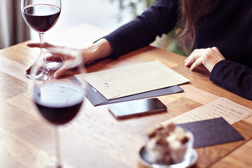 Having lunch with red wine in a cafe or restaurant. Hipster lifestyle. Blank paper envelope, phone. wooden table