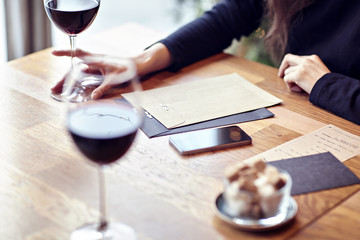 Having lunch with red wine in a cafe or restaurant. Hipster lifestyle. Blank paper envelope, phone. wooden table