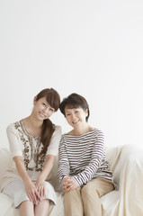 Fototapeta premium ソファーに座り微笑む母と娘