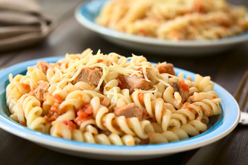 Rotini pasta with tuna and tomato sauce and grated cheese on top, photographed with natural light (Selective Focus, Focus in the middle of the first dish)