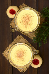 Eggnog with freshly grated nutmeg on the top, thumbprint cookies on the side, photographed overhead with natural light (Selective Focus, Focus on the top of the eggnogs)