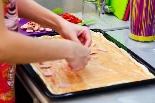 Woman hands grating cheese on the pizza. Young woman preparing the pizza in the kitchen.