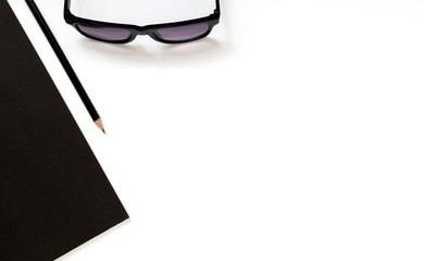 Flat lay photo of office desk with balck book, eyeglasses and pencil with copy space background