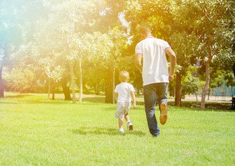 Father and son running and chasing each other in green park