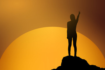 silhouette of fighting woman at sunset or sunrise standing and raising up her hand and two finger in celebration of having reached mountain top summit goal.Happy celebrating.business success concept