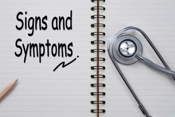 Stethoscope on notebook and pencil with signs and symptoms words