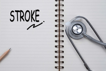 Stethoscope on notebook and pencil with stroke words as medical