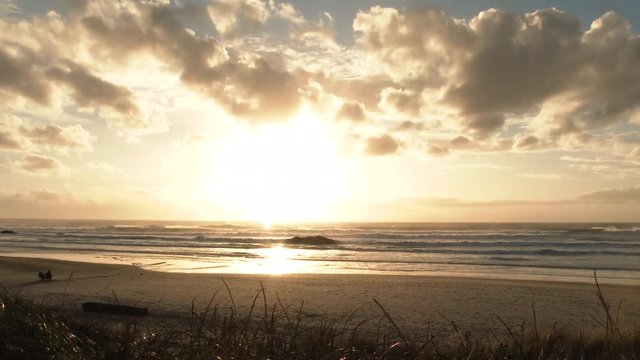 Time lapse from day to night with colorful clouds passing as sun drops below ocean horizon at the Oregon Coast.