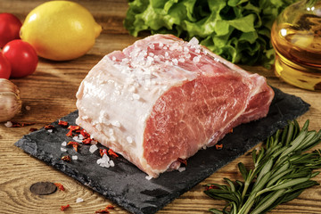 Top view on raw pork loin with salt and herbs.