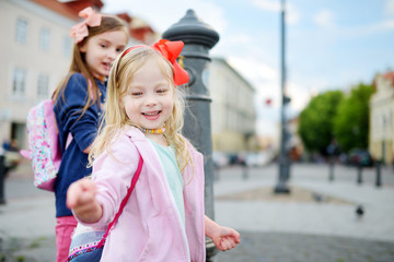 Two sisters having fun with drinking water fountain on sunny summer day