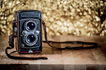 old camera on wood in abstract bokeh golden background.