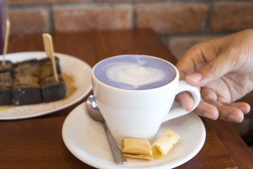 man hand holding a cup of hot milk at coffee shop.