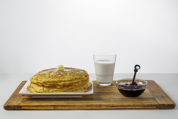 Crepes with milk and black currant jam on wood