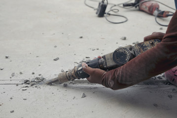 Closeup of workers are hammer drill cement floor in construction site.