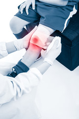 Doctor makes bandage on knee patient, on white background.