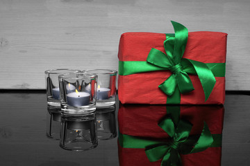 Box with a gift and a candle on a glass table