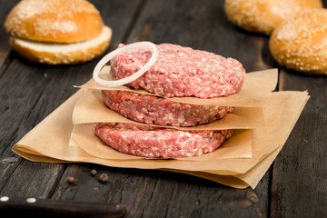 Closeup fresh raw ground beef meat cutlets with onion ring