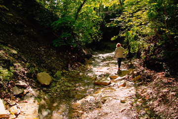 Woman walking along the brook in the mountains