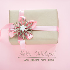 Christmas gift box for girl with pink ribbon and snowflakes on pink. Square image.