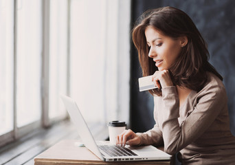 Young woman holding credit card and using laptop computer. Online shopping concept